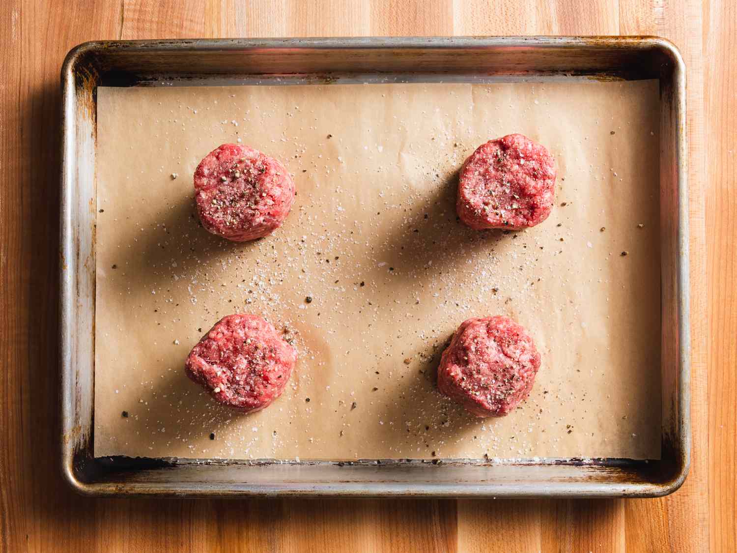 Four 4-ounce portions of ground beef, on a lined baking sheet, formed into 2-inch-high pucks and seasoned with salt and pepper