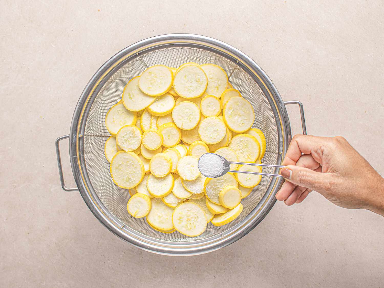 Yellow squash salted in a colander.