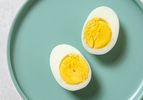 A perfect steamed boiled egg, cut in half lengthwise, on a blue plate.