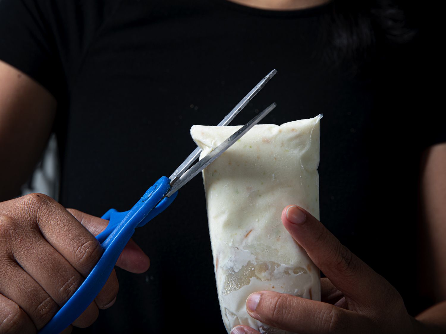 Hands cutting the corner of the boli with scissors