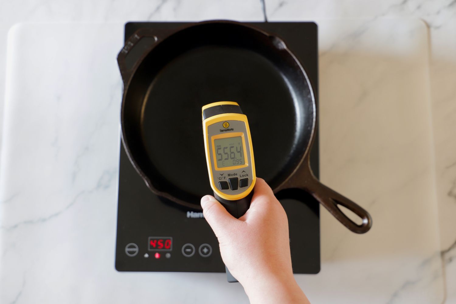 using an infrared thermometer to take the temp of a cast iron skillet on an induction cooktop