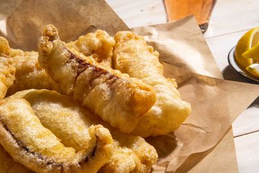 A closeup of a serving platter of fried salt cod fillets.