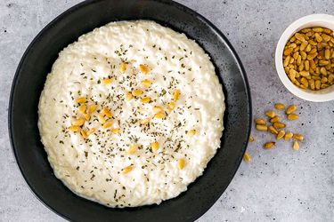 Labaniyeh bil Ruz in a black bowl with toasted pine nuts