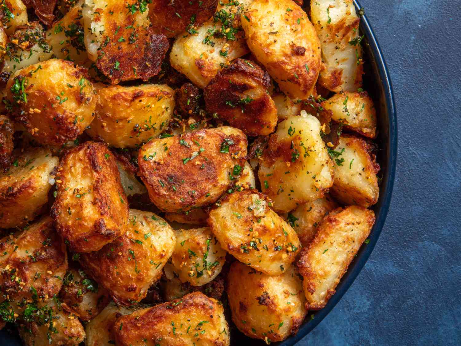 The best crispy roast potatoes ever in a bowl on a blue background.