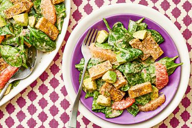 Overhead view of a single serving of a salad next to a serving bowl of salad