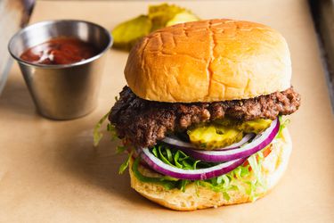 Classic smashed burger on a potato bun with pickles, red onion, tomato, and lettuce.