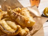 A closeup of a serving platter of fried salt cod fillets.