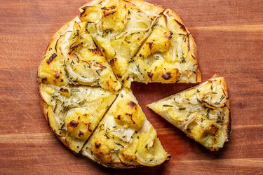 Potato pan pizza on a wooden surface.