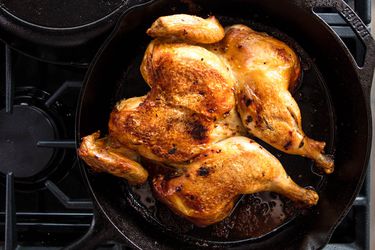 a whole chicken in a cast iron skillet on a stovetop