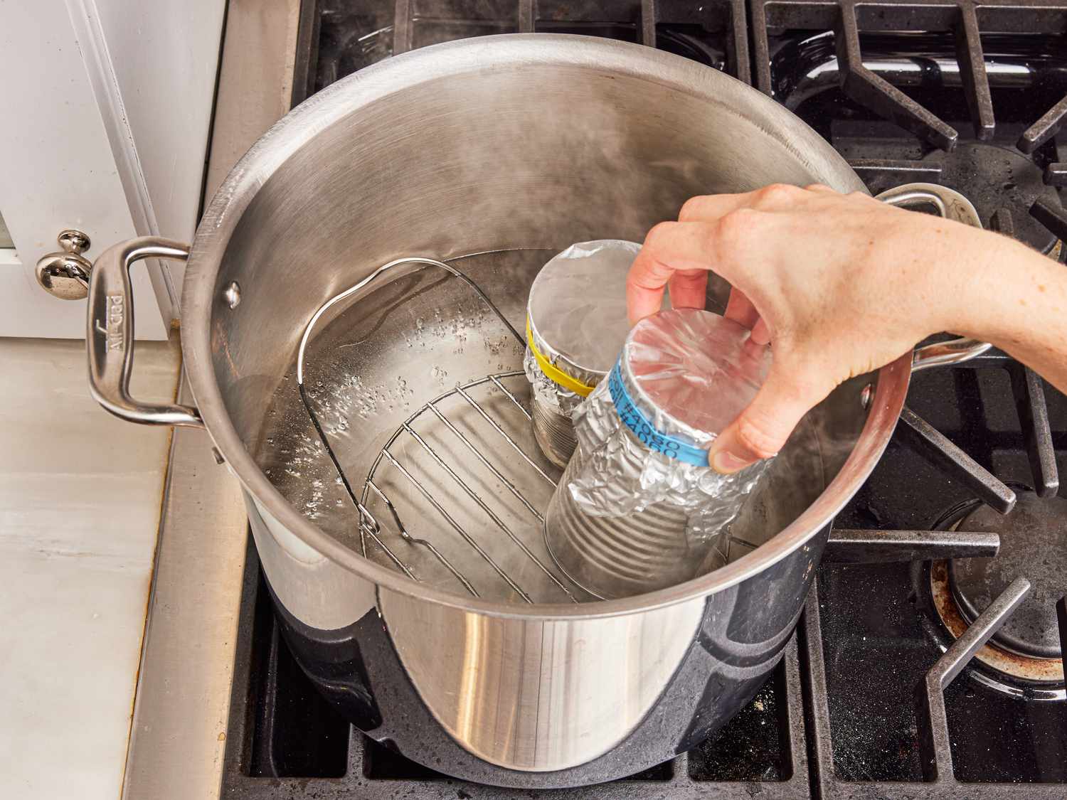 Overhead view of placing cans into a pot of boiling water