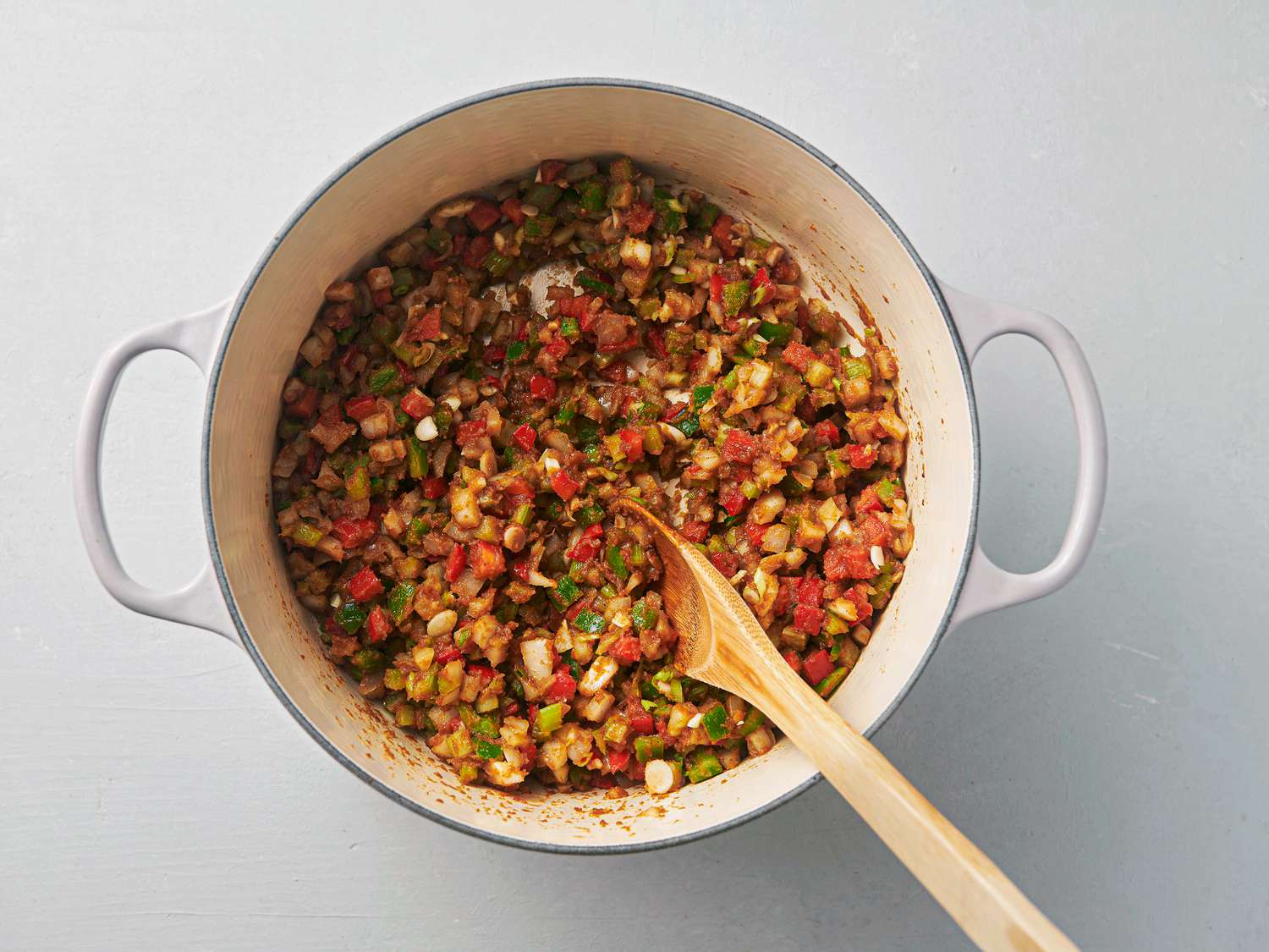 Garlic and scallion stirred into softened onion, celery, and bell pepper coated with the floury paste inside Dutch oven