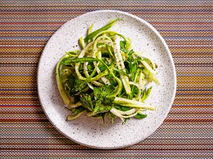 Overhead view of puntarelle salad on a colorful stripped background