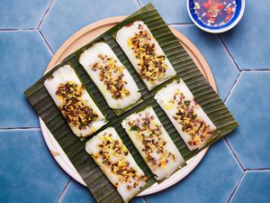 Overhead view of finished banh man on a banana leaf one a blue titled background