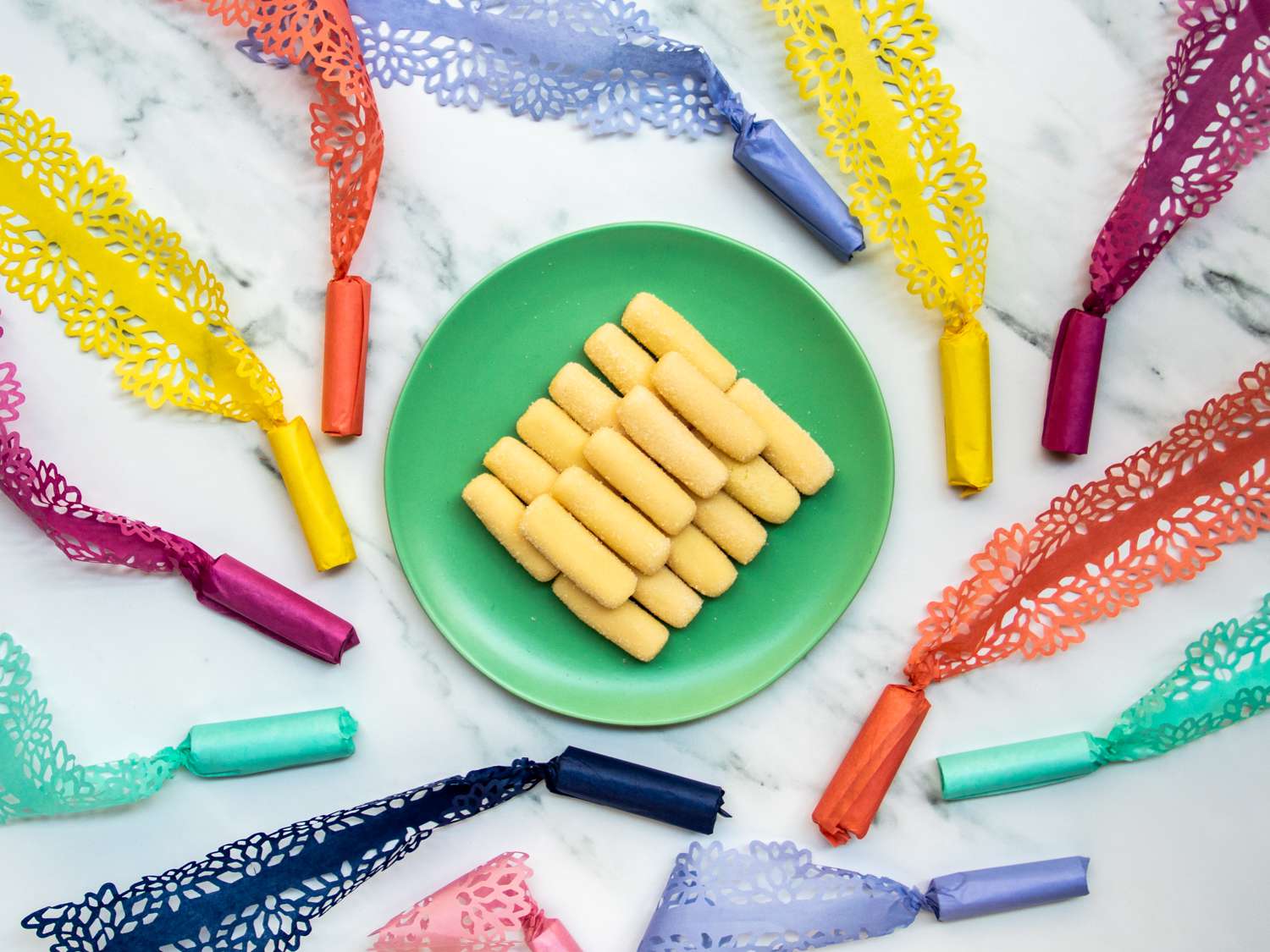 pastillas de leche on a plate surrounded by candy in intricately cut wrappers, an art form known as pabalat