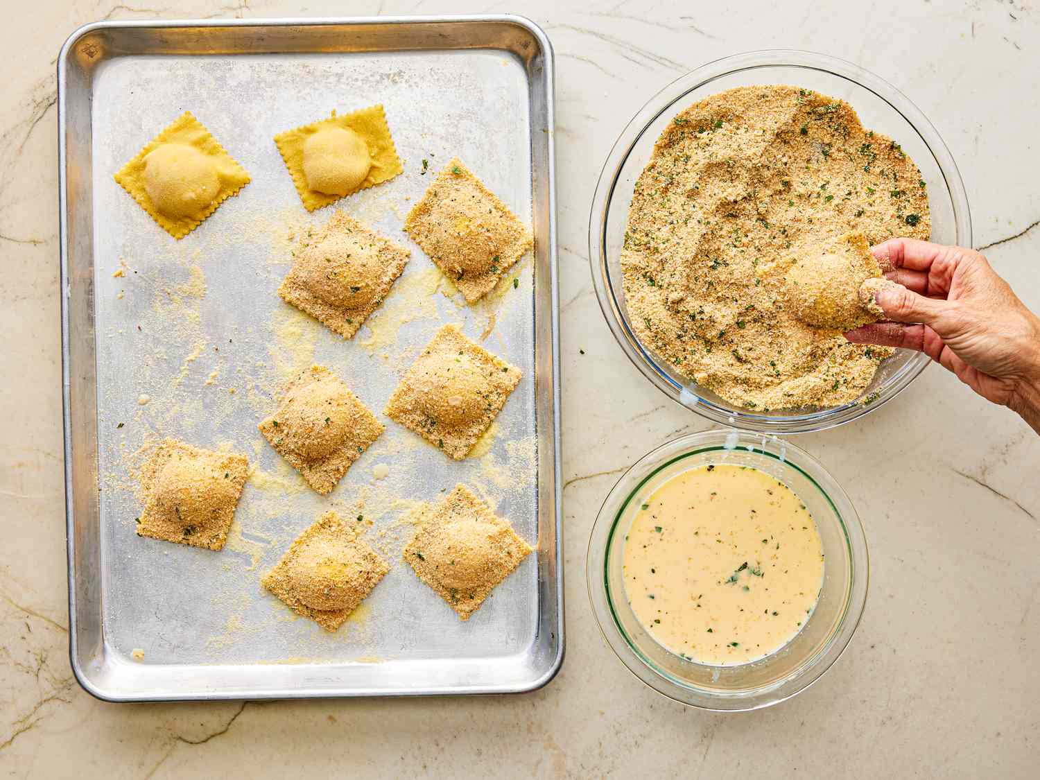 Overhead view of coating raviolis with eggs and bread crumb mixture