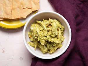 A bowl of pesto chicken salad with crackers on the side