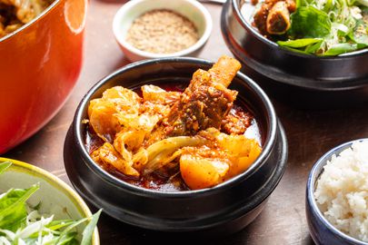 Bowls of gamja-tang with garnishes and sides of white rice.