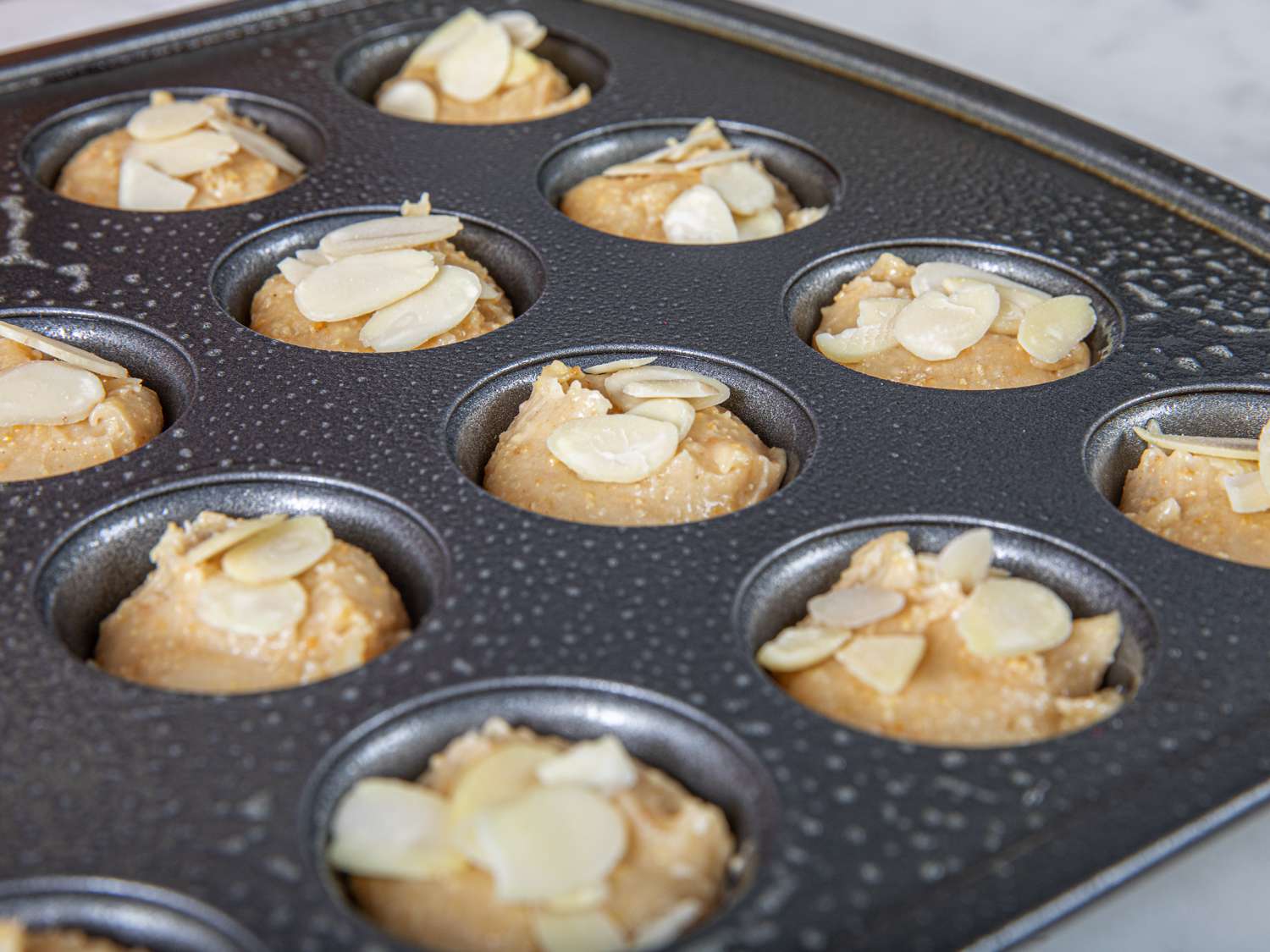 Financier batter in mini cake pan topped with almonds