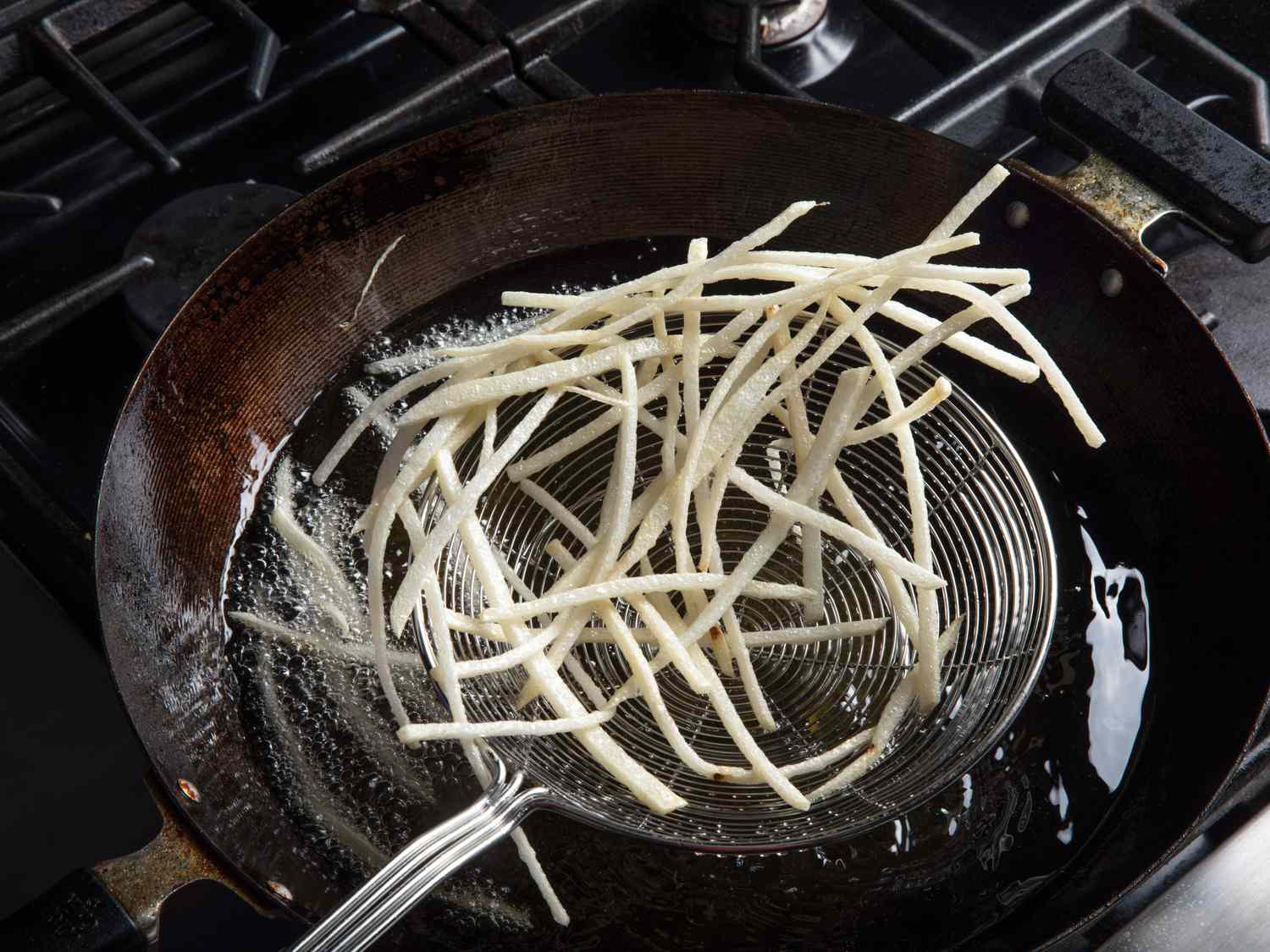 Shoestring fries in a spider strainer after first fry