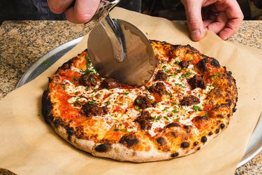 Armenian pizza being cut with a pizza cutter