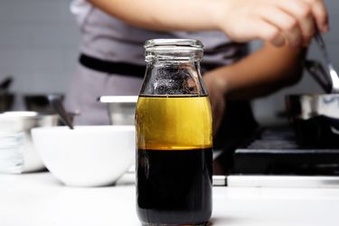 Bottle of all purpose vingeriatte on a counter with a chef cooking in the background