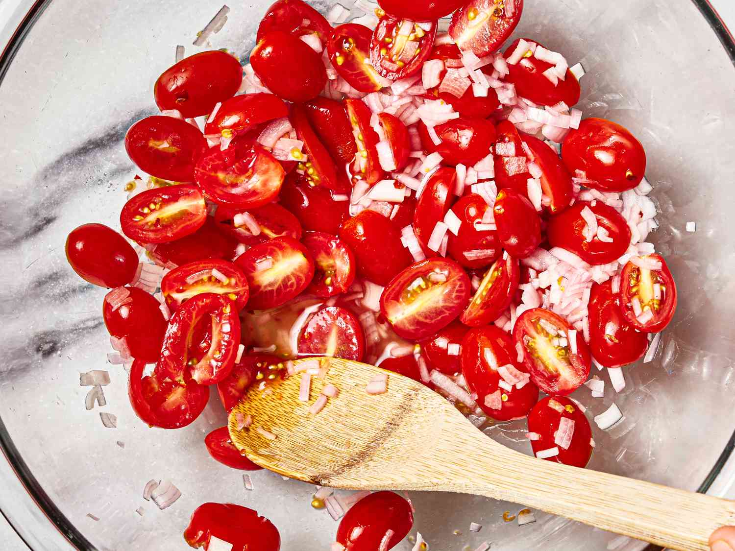 Overhead view of tomatoes and onions in a glass bowl