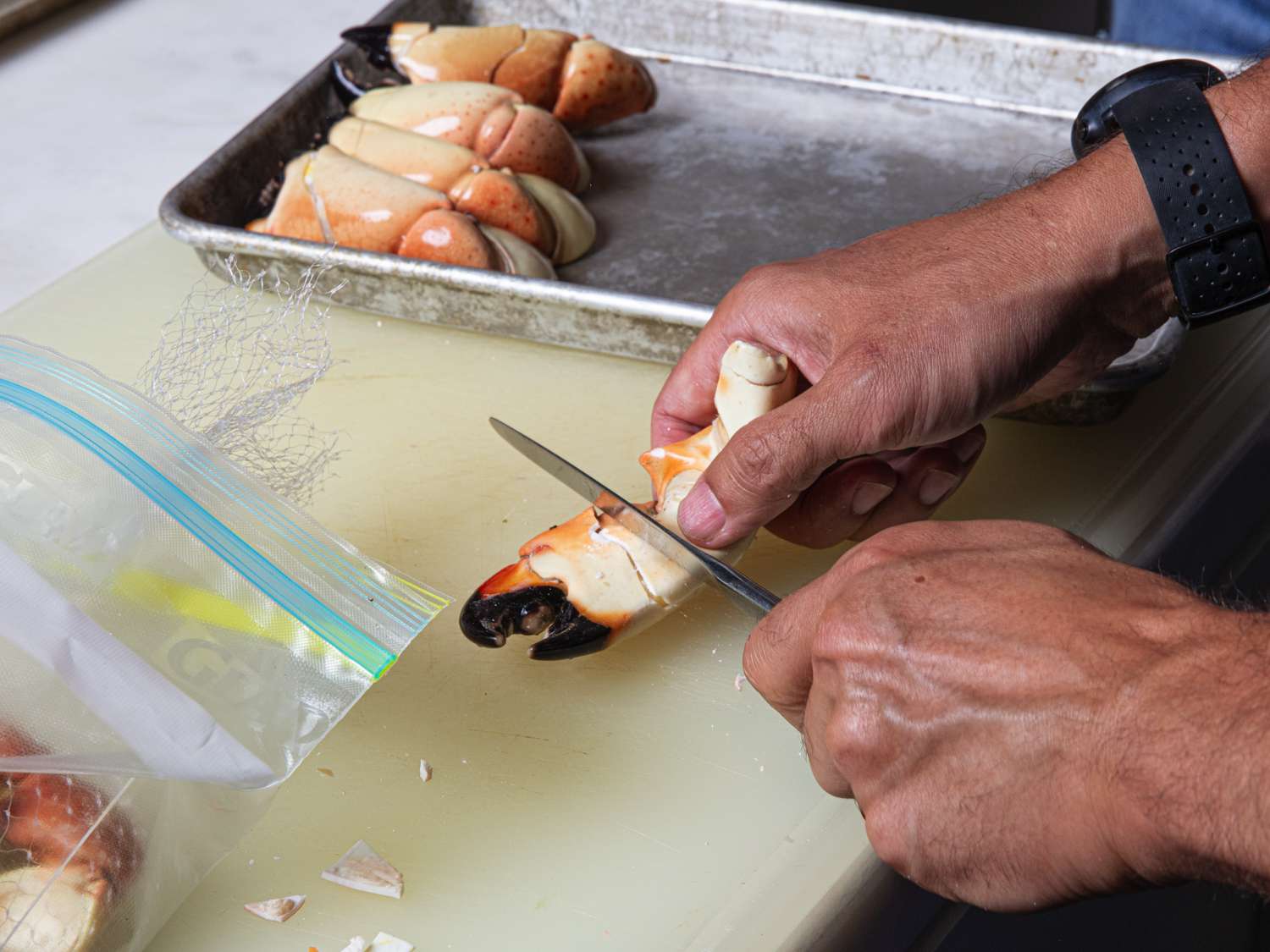 Overhead view of stone crab claws being cracked with a butter knife