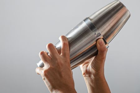 Two hands holding and shaking a cocktail shaker