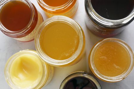 a variety of jars of honey with their tops open