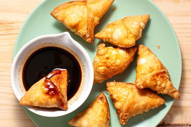 Tamarind chutney in a bowl with fried samosas.