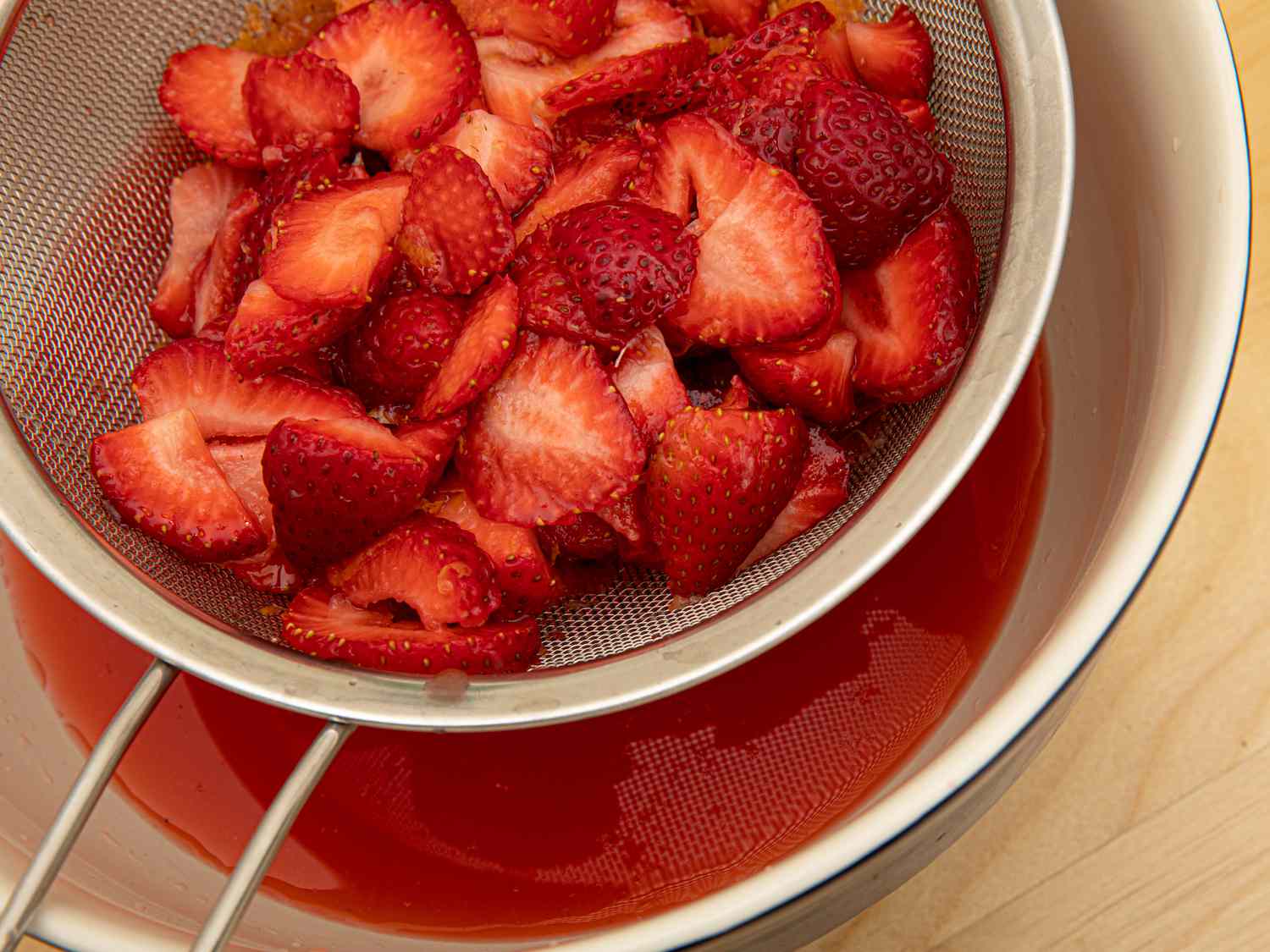 Overhead view of straining strawberry lemonade concentrate