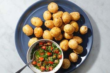 Fried papas criollas on a blue ceramic plate with ajÃ­.