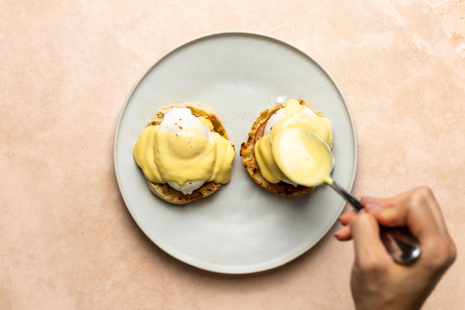 The plate holding the Eggs Benedict, with each half being topped with foolproof hollandaise sauce.