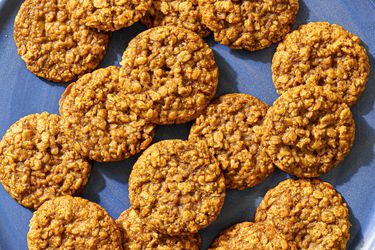 A blue ceramic plate holding many maple brown sugar oatmeal cookies.