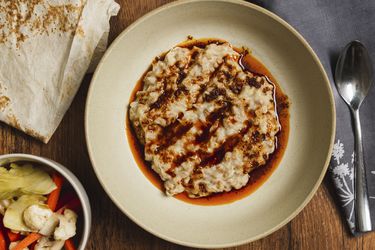 Overhead view of harissa with pickled vegetables and lavash