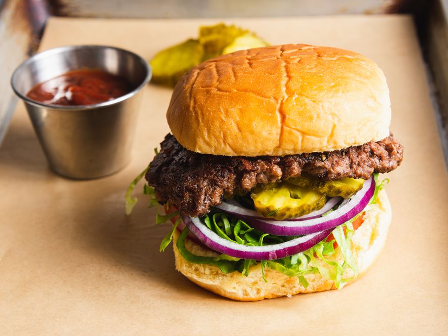 Classic smashed burger on a potato bun with pickles, red onion, tomato, and lettuce.