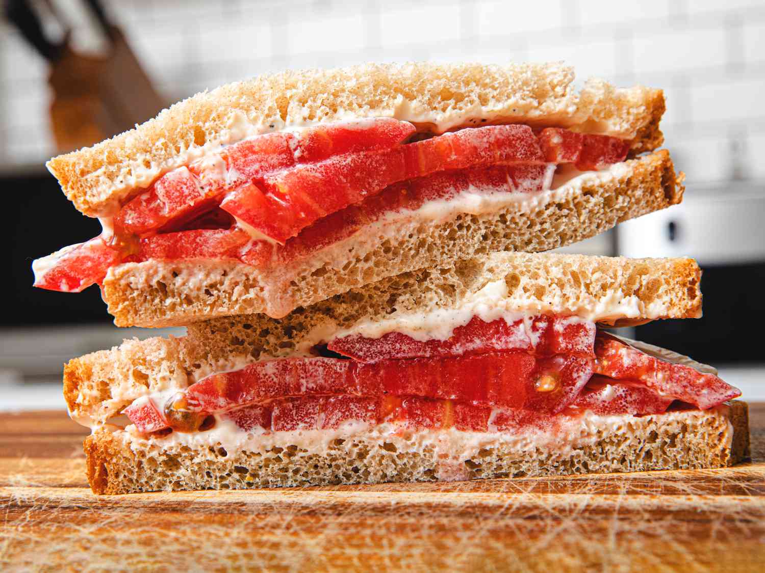 Classic tomato sandwich on a cutting board, cut diagonally and stacked