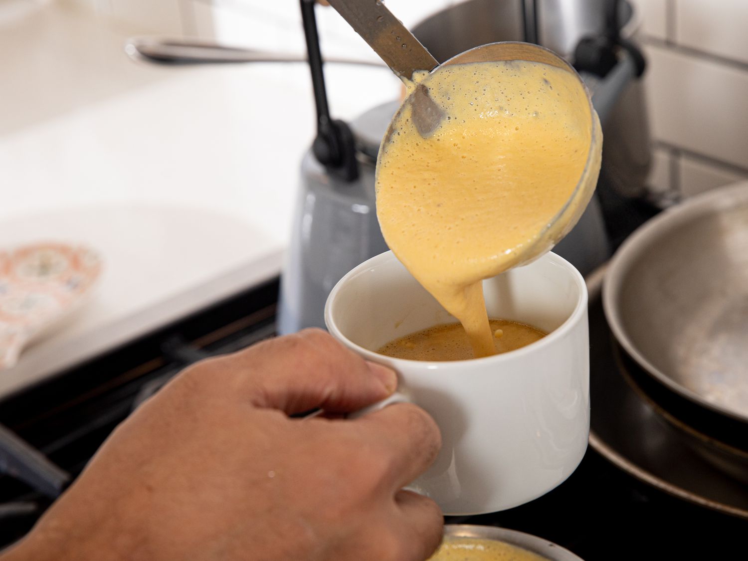 Side view of ladling pumpkin spice foam into a cup with coffee