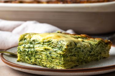 一个slice of spinach lasagna, shot from the side so that all of the layers are visible.