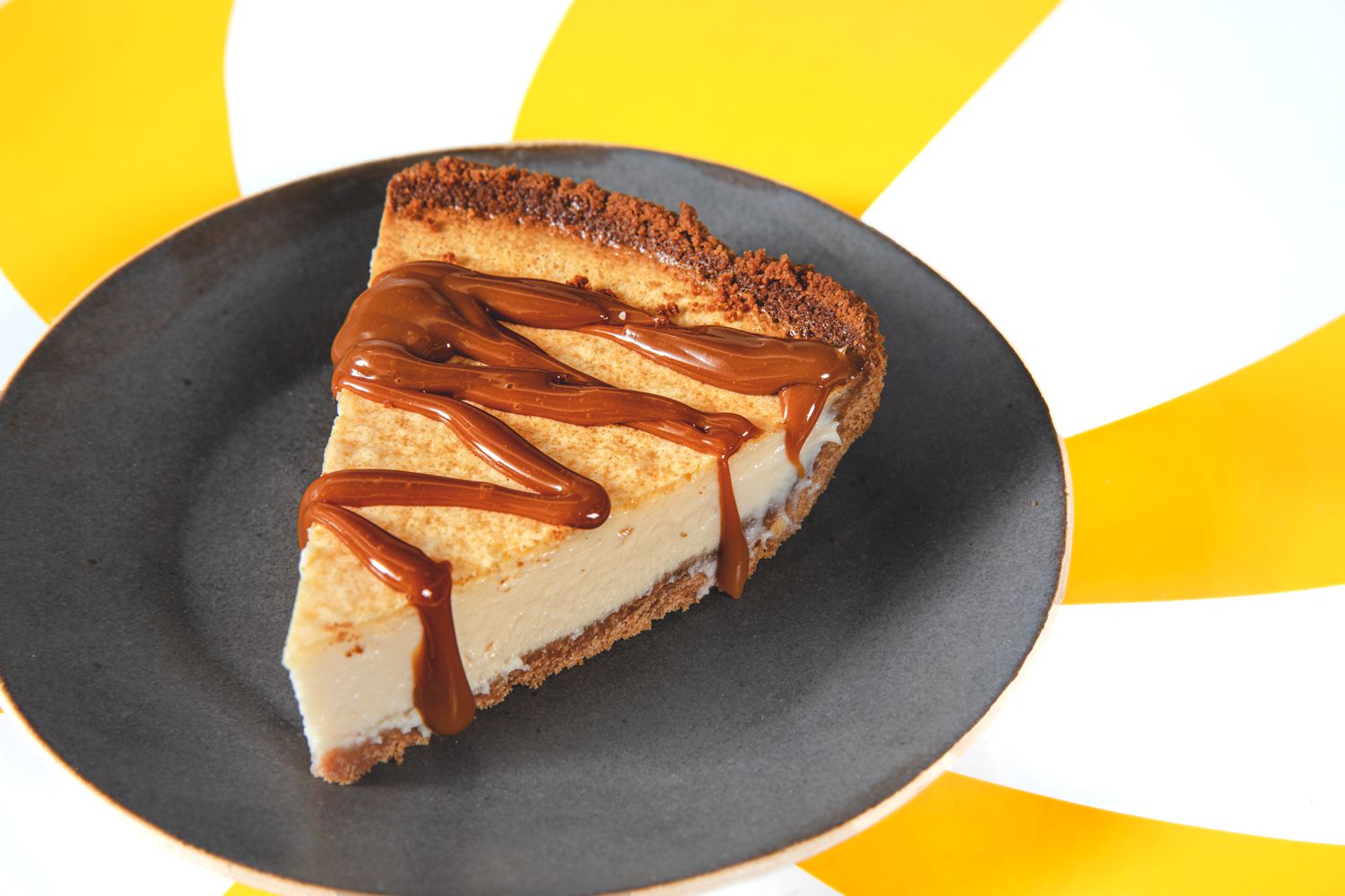 A slice of pays de queso drizzled with dulce de leche on a yellow starburst backdrop