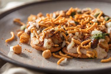 A plate of composed papri chaat (a type of Indian street food made of multiple components) highlighting the sev topping.