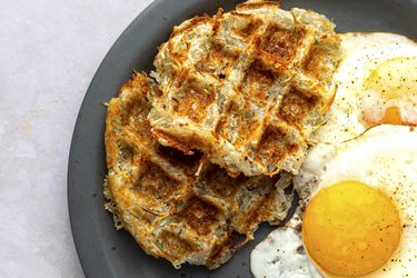 Waffle-iron hash browns on a plate with sunny side up eggs.