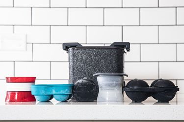 Several sphere ice molds against a white, subway tile background