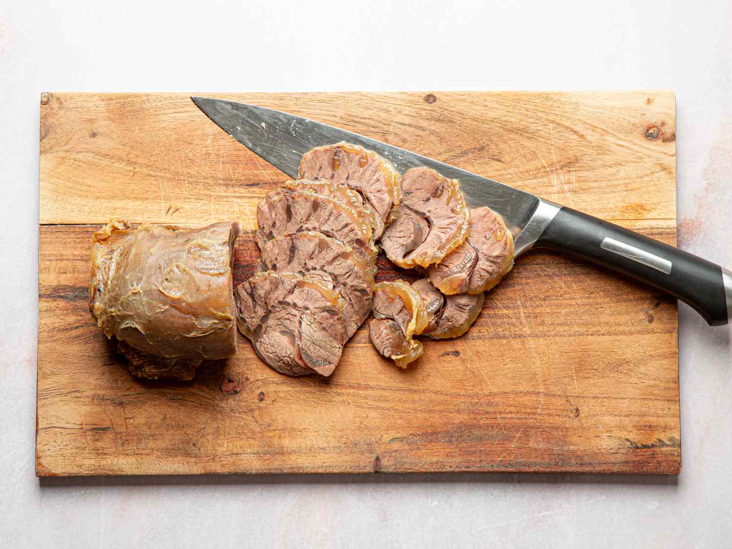 Overhead view of meat being sliced on a cutting board