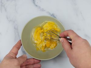 a miniature whisks beats three eggs in a bowl