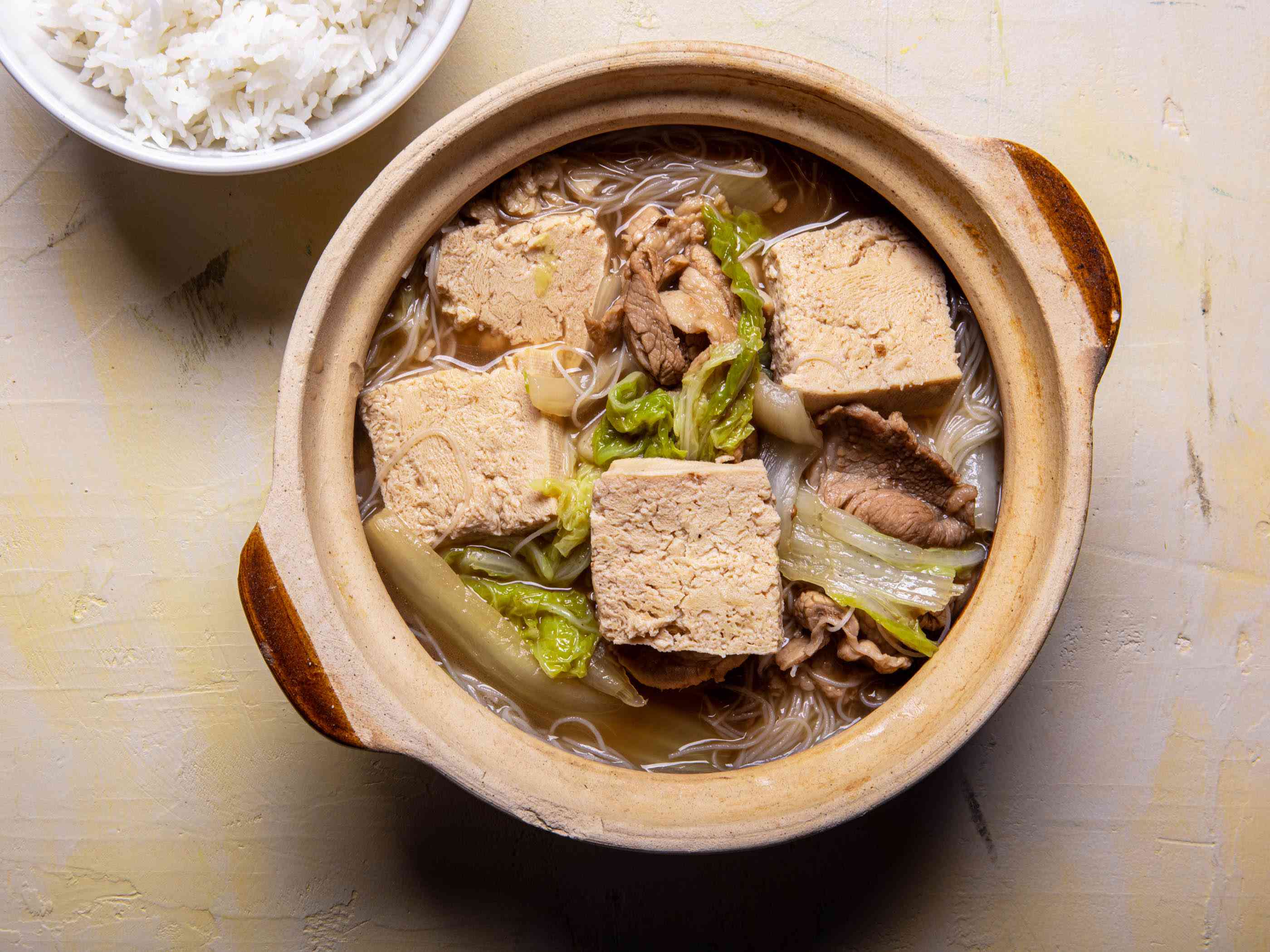 Overhead view of frozen simmered tofu soup with pork and cabbage in a serving bowl