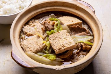 上一碗冷冻炖豆腐汤，配上猪肉、卷心菜和米粉，旁边还有米饭gydF4y2Ba