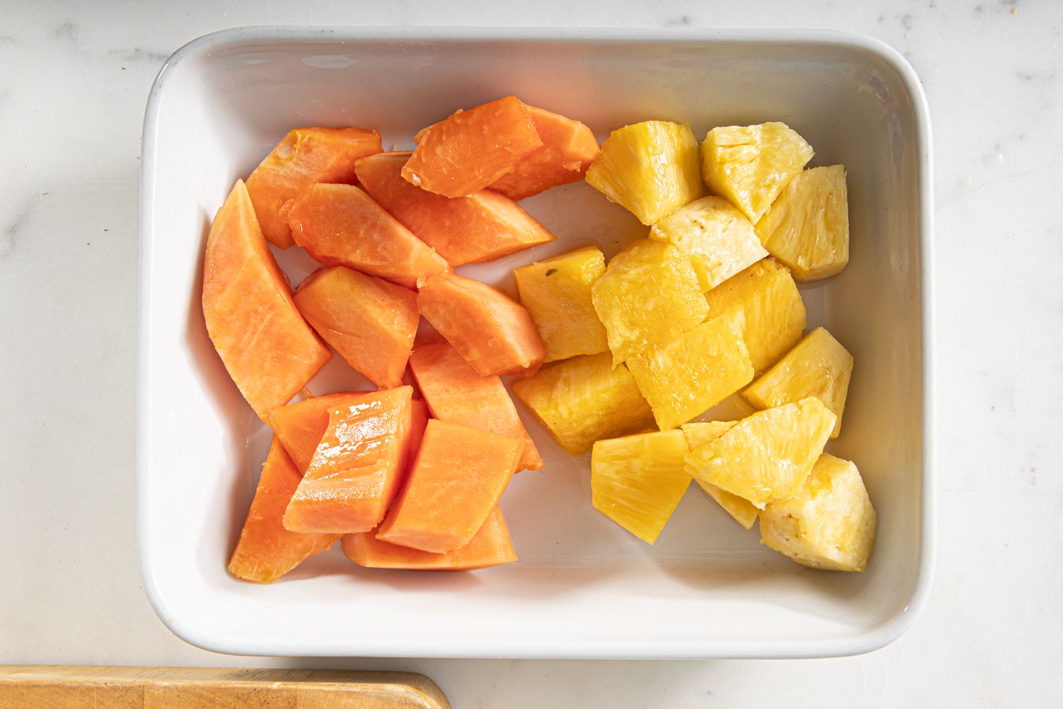 Cubed papaya and pineapple in a serving tray.